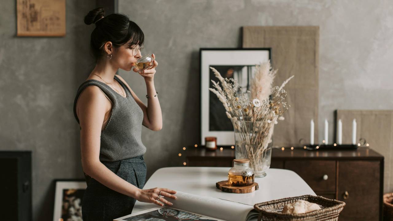 žena stojaca pri stole pijúca nápoj